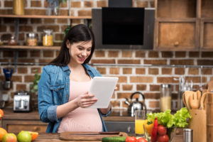 pregnant woman reading tablet in kitchen